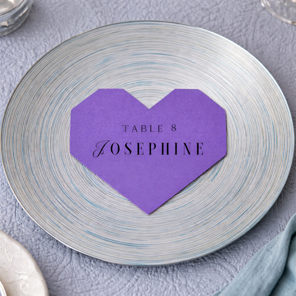Purple heart-shaped place card with 'Table 8 Josephine' on a silver plate.