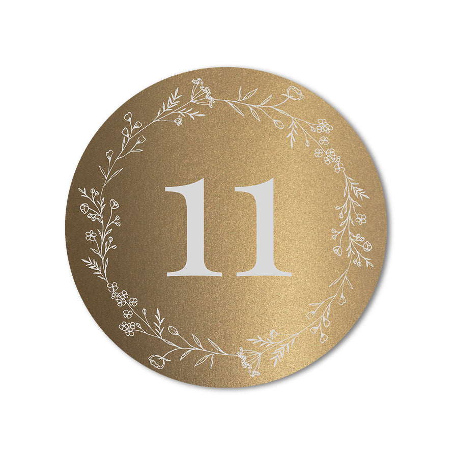 Round gold table number card with floral wreath design