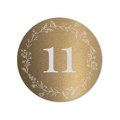 Round gold table number card with floral wreath design