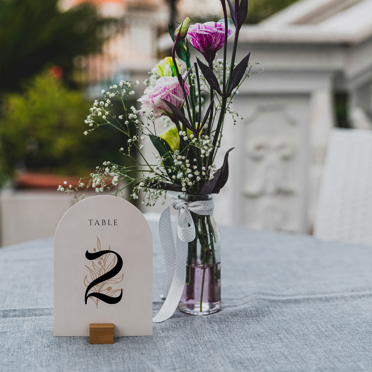 Table number card with a vase of flowers on a table outdoors