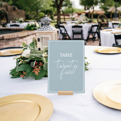 Table setting with a wedding table number sign in an outdoor wedding venue.