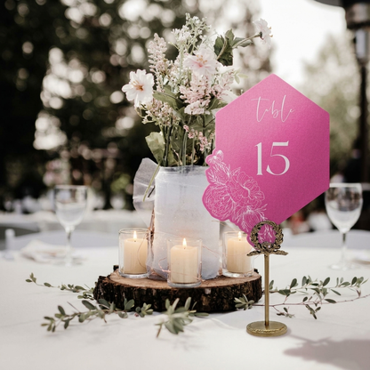 Table setting with floral centerpiece, candles, and pink table number 15 in an outdoor setting.