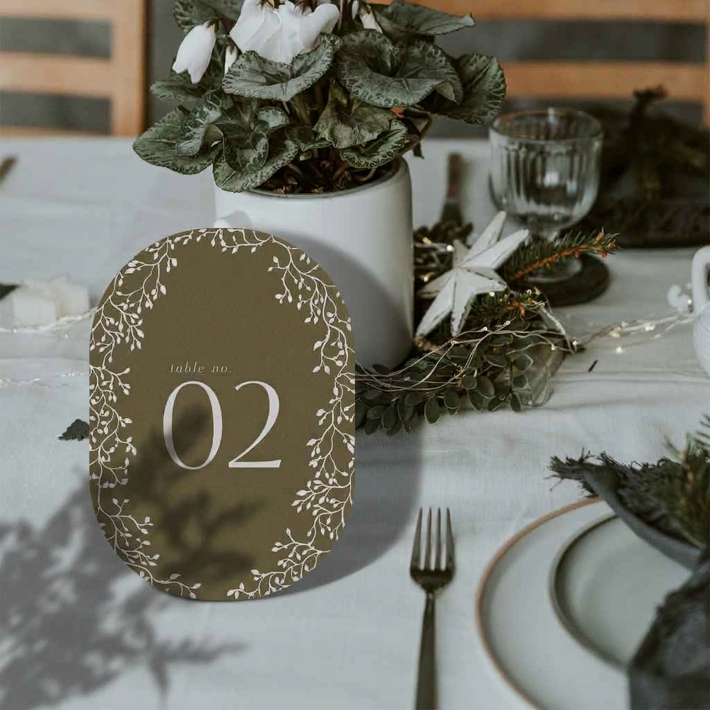 Decorative table number on a table with floral arrangements and cutlery.