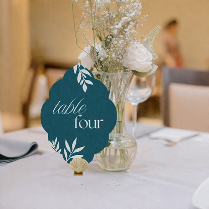 Table number card with floral arrangement on a table in a blurred indoor setting