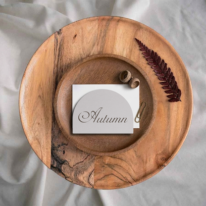 Wooden plate with a name card labeled 'Autumn' and decorative elements on a light fabric background
