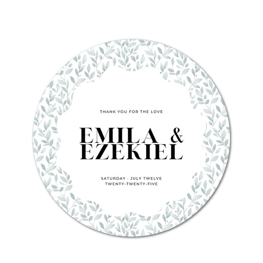 Round wedding favor card with green leaf pattern and text 'Emila & Ezekiel' on a white background