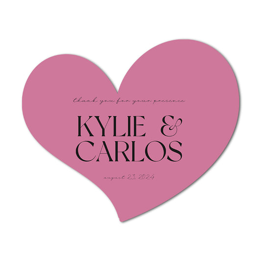 Pink heart-shaped custom favor label  with 'Kylie & Carlos' and a date on a white background