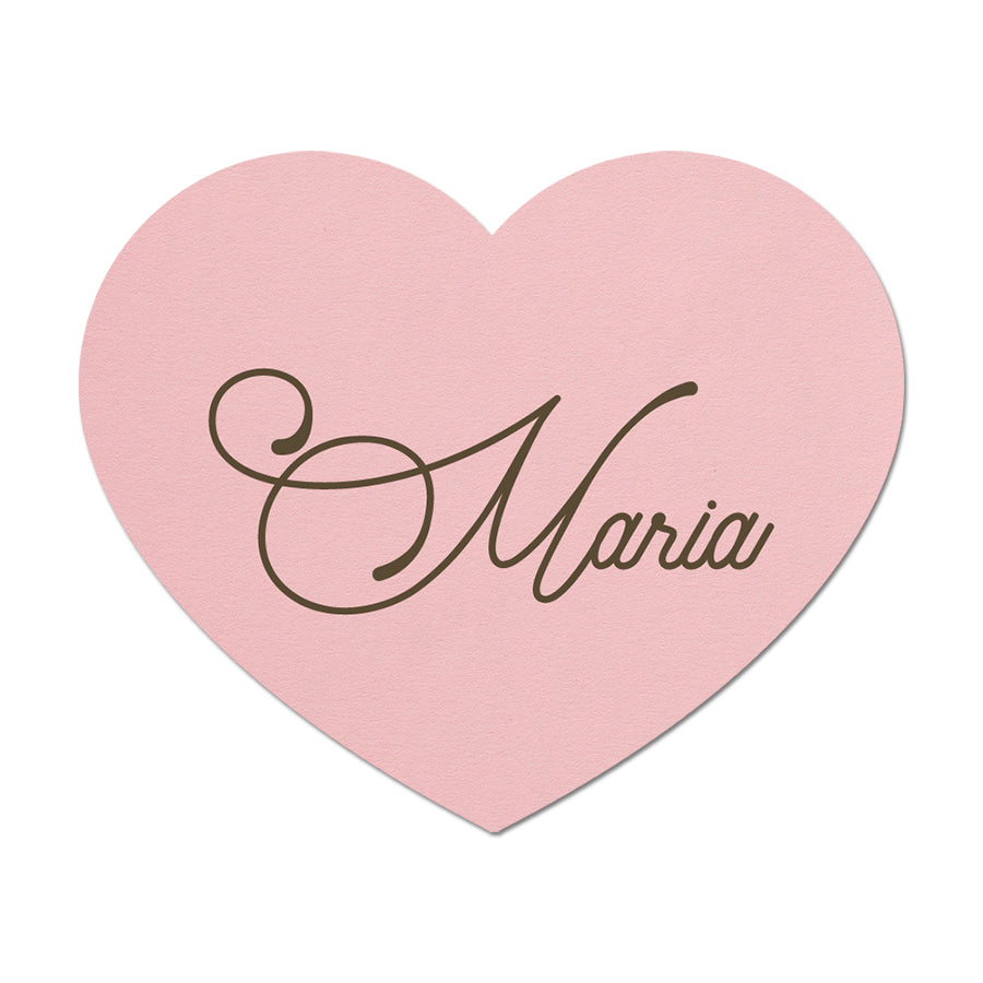 Pink heart-shaped place card with 'Maria' written on it against a white background