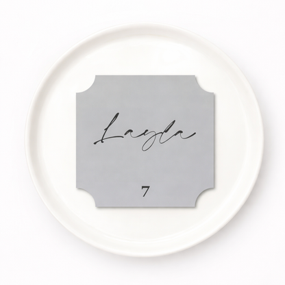 Round white plate with a gray name card featuring the name 'Layla' and number '7'.