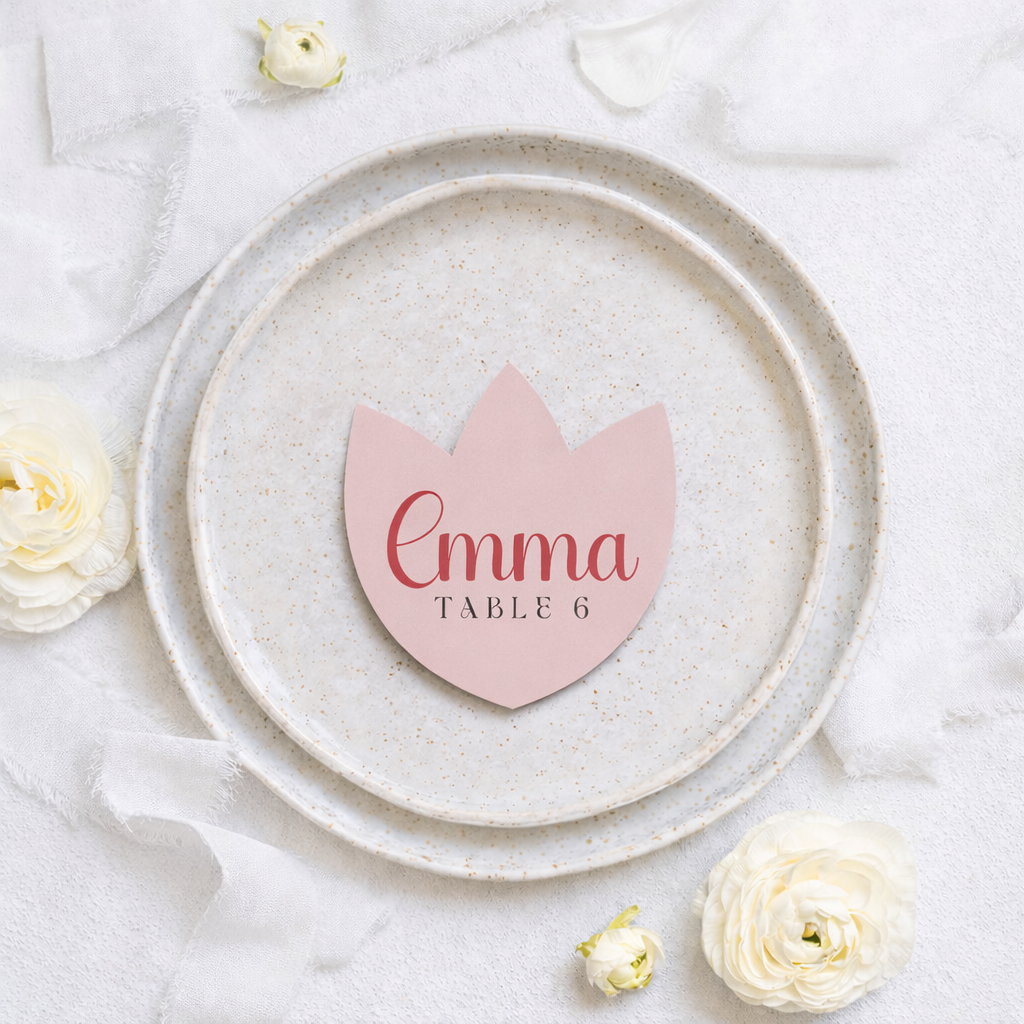 Pink tulip-shaped place card with 'Emma Table 6' on a white plate with flowers.